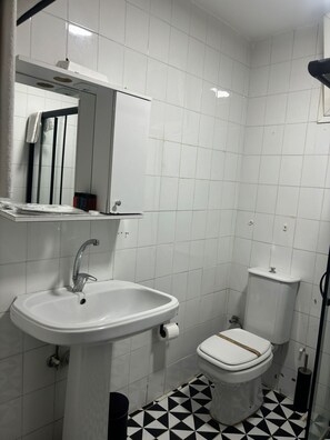 Ein Badezimmer mit weißem Waschbecken, Toilette und einem Spiegel über dem Waschbecken.
