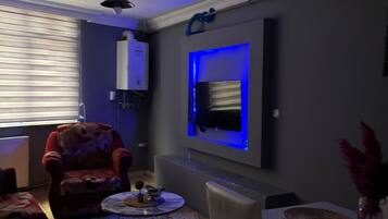 A living room with a sofa, a coffee table, and a TV mounted on the wall.