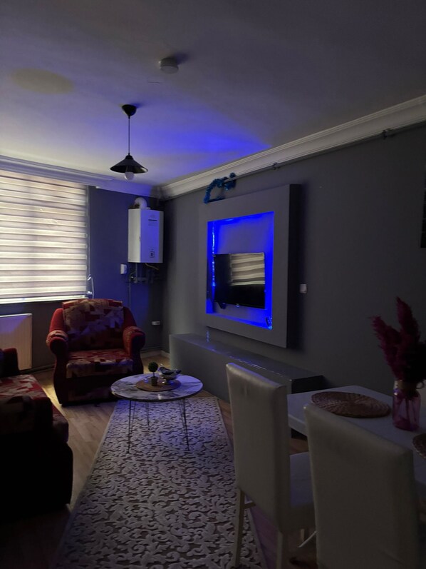 A living room with a sofa, a coffee table, and a TV mounted on the wall.