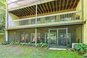 Ein zweistöckiges Gebäude mit Balkon, großen Fenstern und einem Garten.