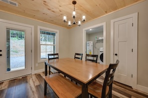 A dining room with a wooden table and chairs, a chandelier, and a view of the outdoors through a window. - Walk to Lake & Paris Landing State Park! Quiet Gem (Buchanan)