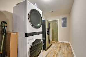 A laundry room with stacked washer and dryer units, a power strip, and a door leading to another room. - Family Home < 1 Mi to Lake & Paris Landing! (Buchanan)
