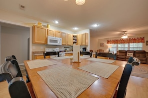 A spacious dining area with a large wooden table, multiple chairs, and a kitchen in the background. - Family Home < 1 Mi to Lake & Paris Landing! (Buchanan)