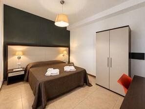 A hotel room with a bed, bedside lamps, a wardrobe, and a small table with a chair. - Apartment in Mazzarino with 1 bedrooms sleeps 2 (Mazzarino)