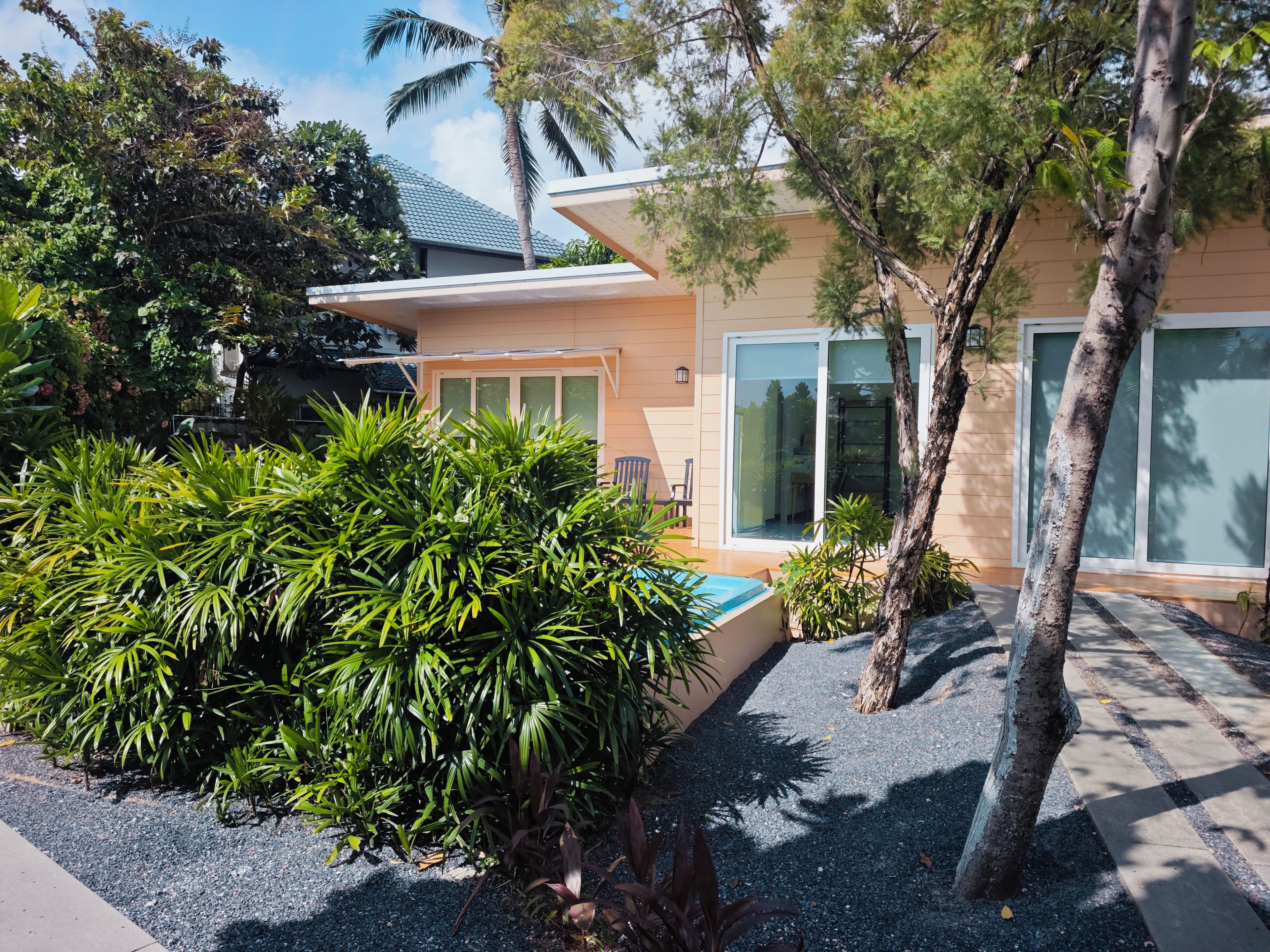 A modern house with a swimming pool, surrounded by lush greenery and a clear sky.
