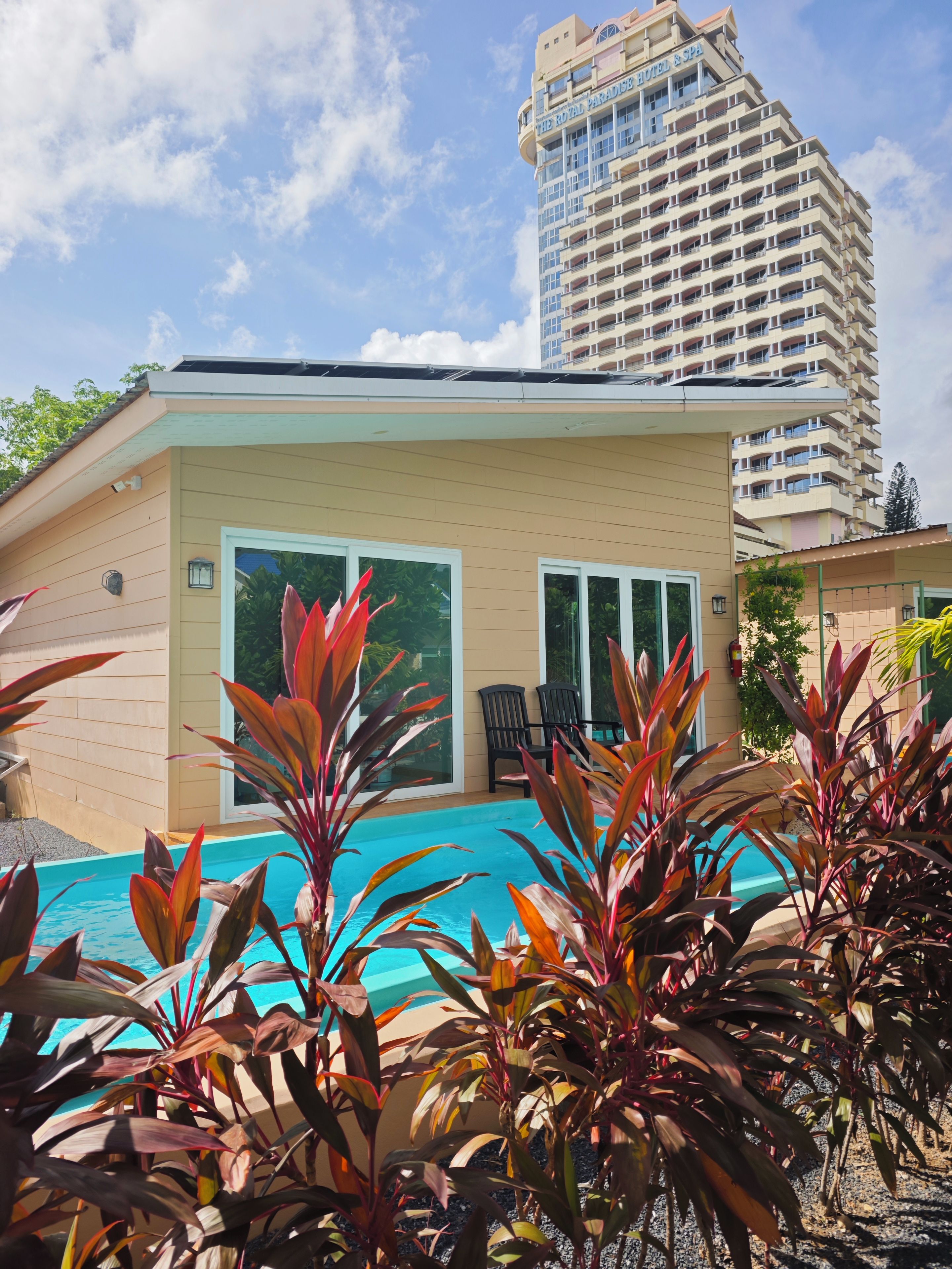 Hotel com piscina, rodeado por plantas tropicais.