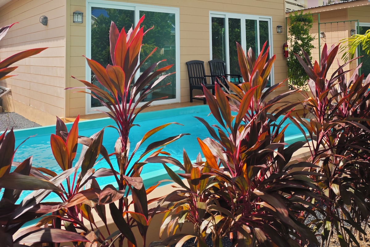 Un hotel con piscina, rodeado de plantas tropicales.
