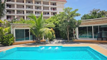 Un hotel con piscina, varios balcones y abundante vegetación.