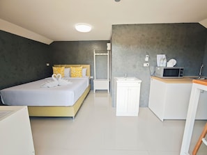 Una habitación de hotel con cama, kitchenette, baño y espejo.