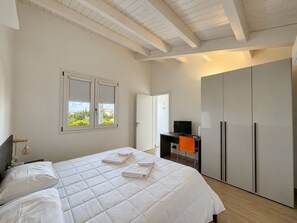 Een slaapkamer met een bed, een bureau, een televisie en een kledingkast.