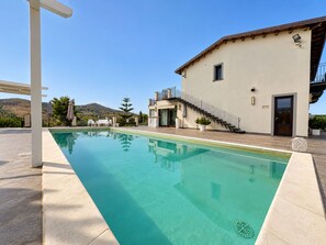 A swimming pool with a clear blue water surface, a white pergola, and a building with a balcony and a staircase. - Vacation Home in Mazzarino with 1 bedrooms sleeps 2 (Mazzarino)