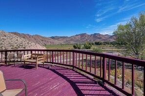 Une terrasse en bois avec une rambarde violette, donnant sur un paysage montagneux.