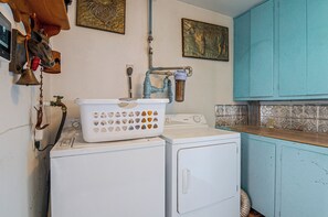 Ein Waschbereich mit Waschmaschine, Wäscheständer und Warmwasserbereiter.