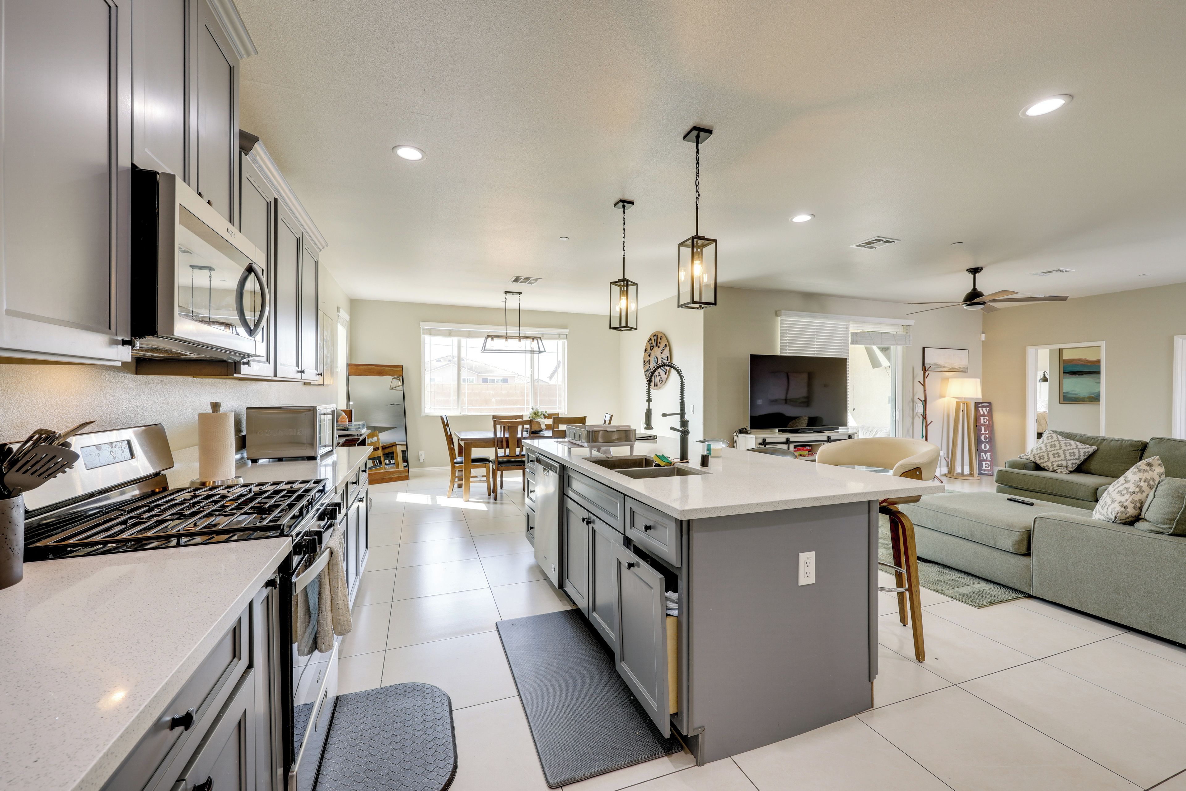 A modern kitchen with a central island, stainless steel appliances, and pendant lighting.
