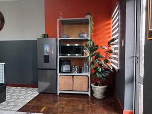 Keittiössä on ruostumattomasta teräksestä valmistettu jääkaappi, mikroaaltouuni, kahvinkeitin ja ruukussa oleva kasvi.