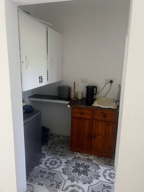 Eine kleine Küchenzeile mit Kühlschrank, Kaffeemaschine und Spüle.