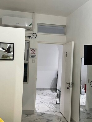 Ein Flur mit einer weißen Tür, einem Rauchverbotsschild und einem gerahmten Bild von einem Vogel.