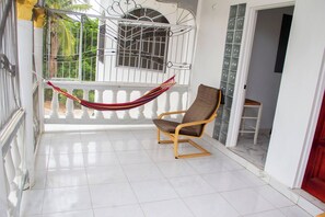 A room with a hammock, a wooden chair, and a white tiled floor.
