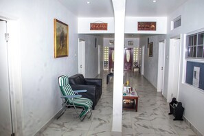 A hallway with a black leather sofa, a striped chair, and a table with a cat. - Complete Property Rental – Private & Comfortable (Clarendon Park)
