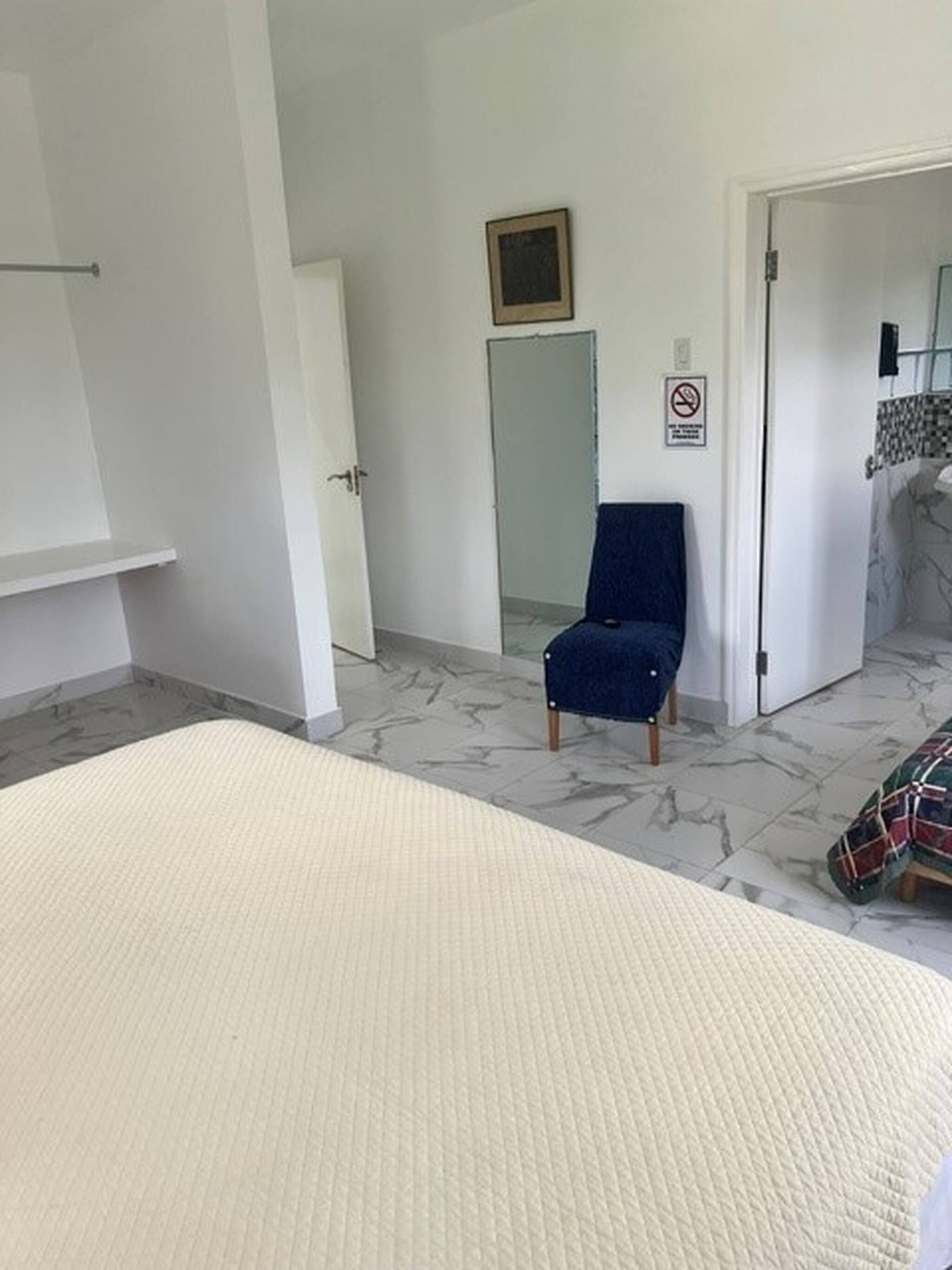 Et hotelværelse med en seng, en stol, en dør og et badeværelse, der kan anes gennem en åben dør.