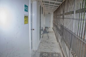 A corridor with a fire exit sign, a caution sign for a slippery floor, and a door with a number.
