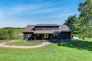A two-story log cabin with a covered porch and a small deck, surrounded by a well-maintained lawn and trees. - Amish Country Gem w/ Pond View! 'Crooked Zebra' (Warsaw)