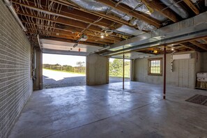 An unfinished interior space with exposed ceiling beams, a concrete floor, and brick walls. - Amish Country Gem w/ Pond View! 'Crooked Zebra' (Warsaw)
