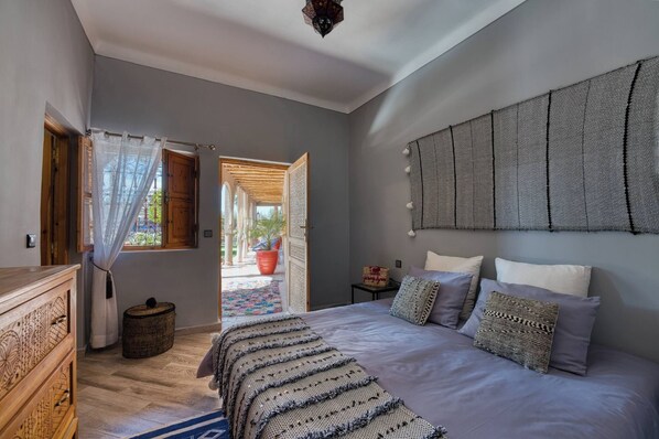 Un dormitorio con una cama grande, un aparador de madera, una ventana con cortinas y vistas al exterior.