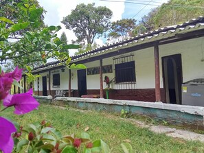 Un edificio con tejado de tejas, un porche cubierto y un pequeño jardín con flores.