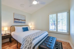 A hotel room with a bed, bedside lamps, a ceiling fan, a window with blinds, and a painting on the wall. - 3 Mi to Downtown!  Sauna & Pool in Palm Springs (Palm Springs)
