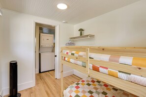 A bedroom with a bunk bed, a washing machine, and a small shelf with a lamp. - Stroll to Olde Town Arvada! Charming Gem (Arvada)