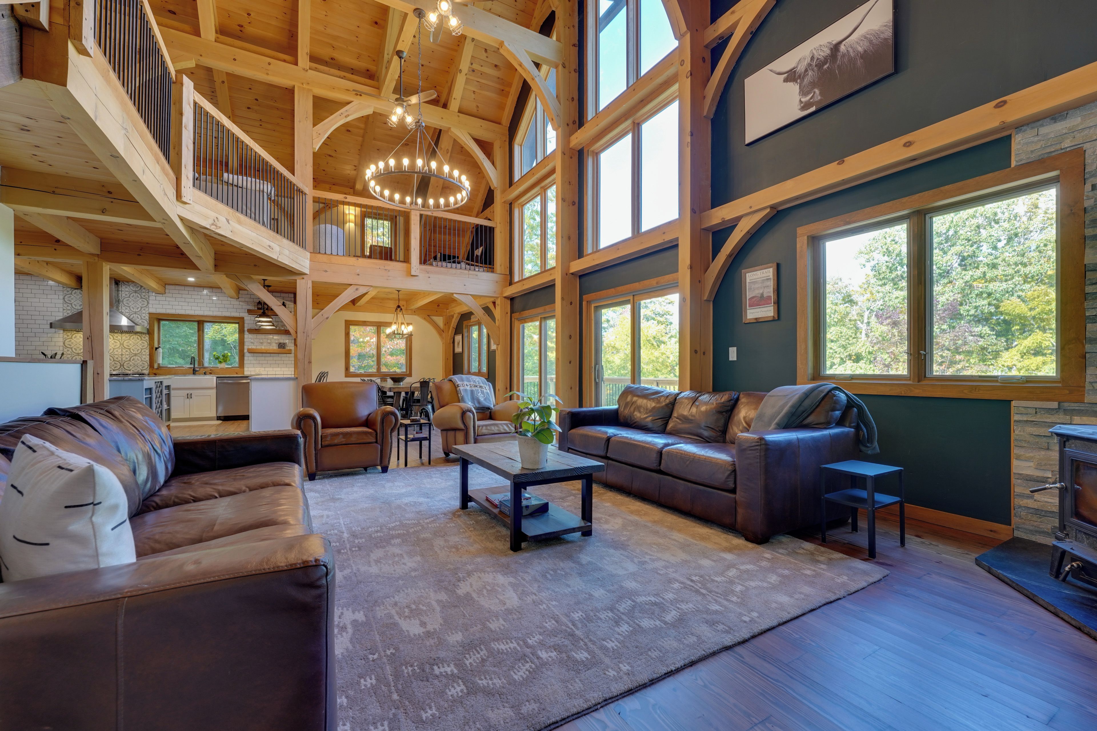 A spacious living area with a high ceiling, wooden beams, and a fireplace.