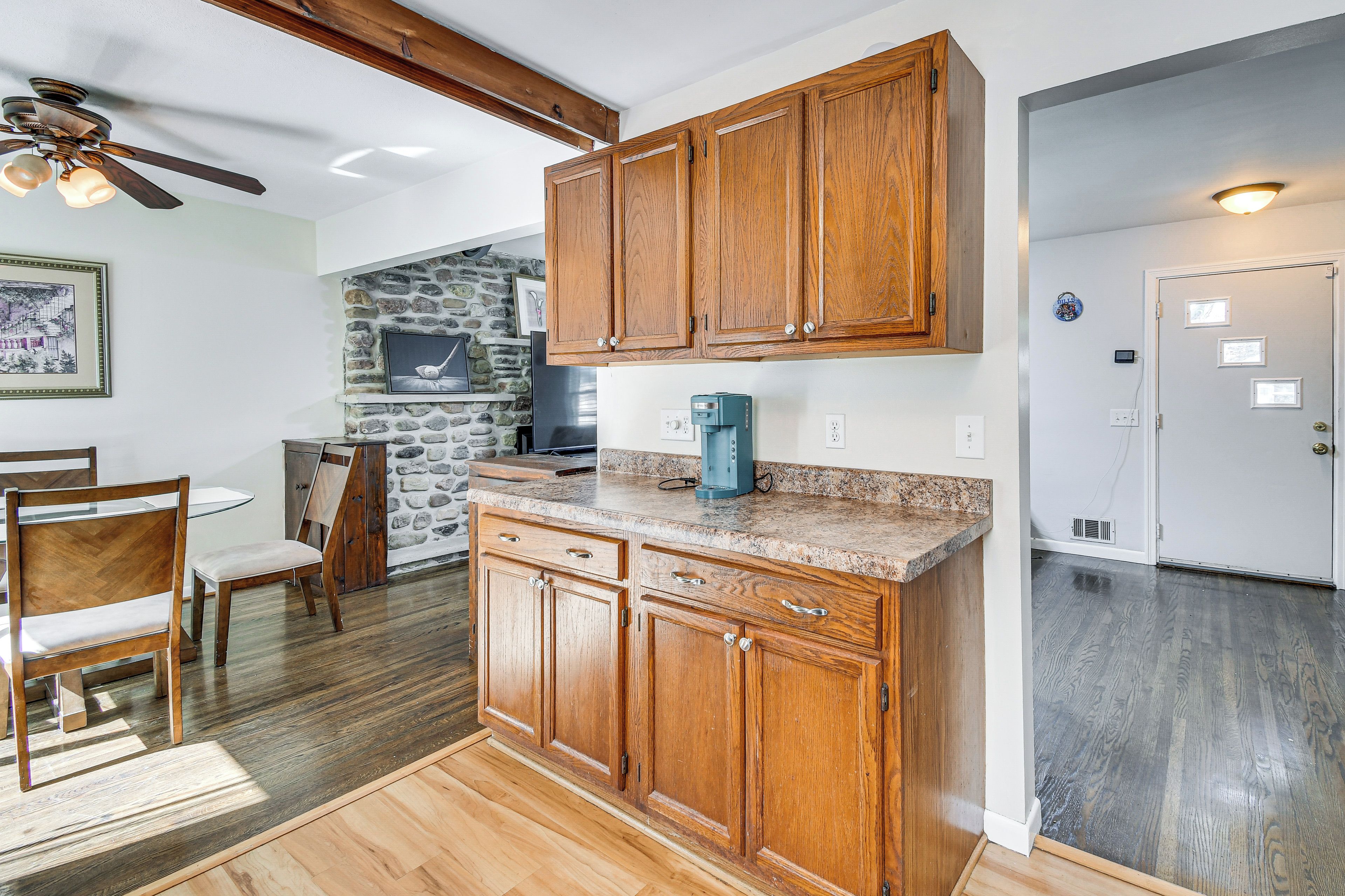 A kitchen with wooden cabinets, a stone wall, and a coffee maker on the counter.