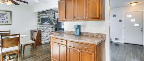 A kitchen with wooden cabinets, a stone wall, and a coffee maker on the counter.