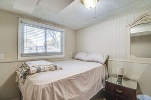 Ein Schlafzimmer mit einem Bett, einem Fenster mit Jalousien, einem Schminktisch und einem Spiegel.