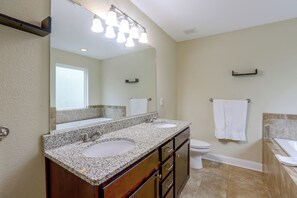 Un baño con lavamanos doble, inodoro y bañera.