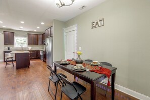 A modern kitchen with dark wood cabinets, a stainless steel refrigerator, and a dining area with a table set for two.