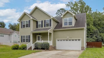 A two-story house with a front porch, a garage, and a well-maintained lawn.