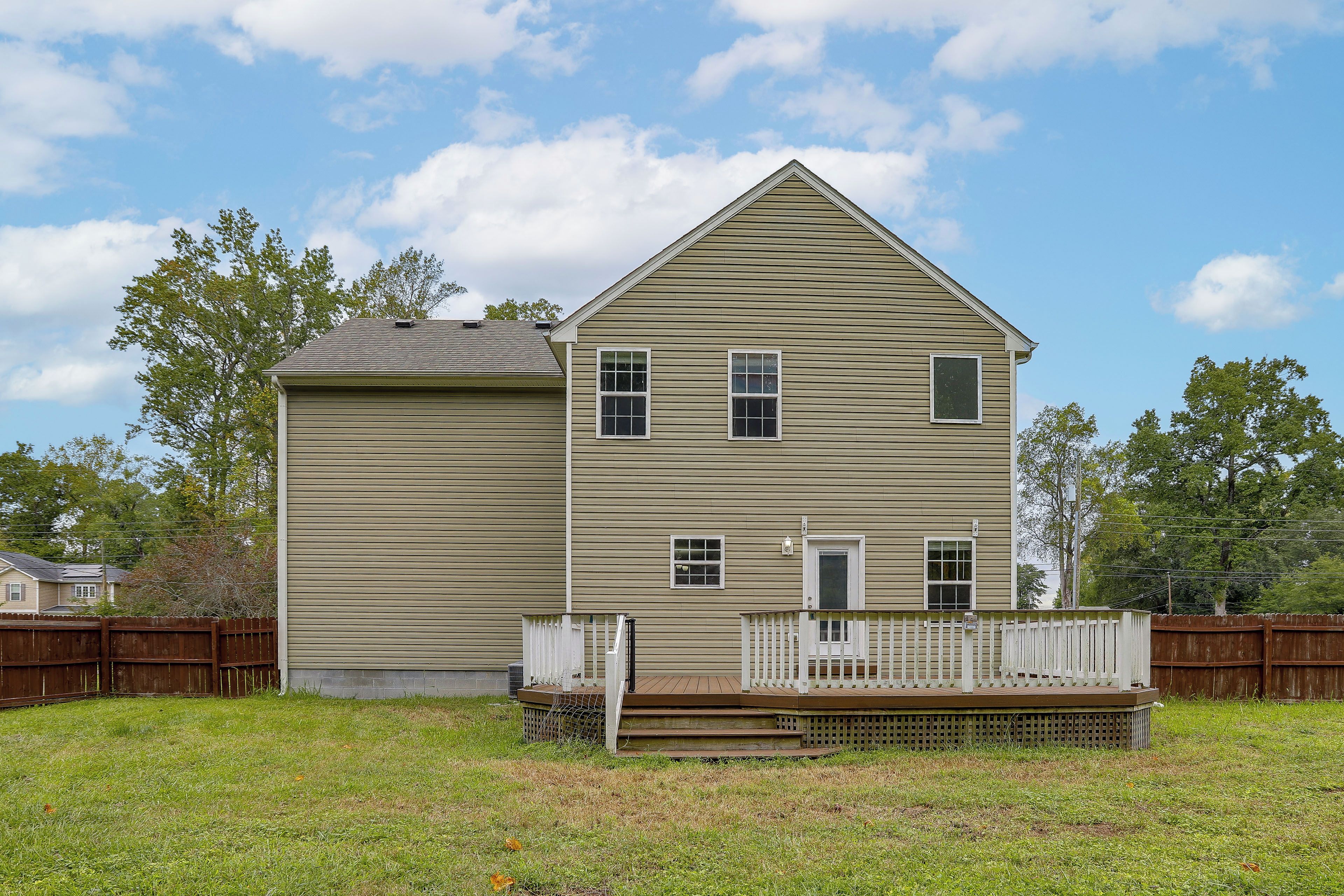 A two-story house with a front porch and a fenced yard.
