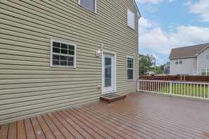 A residential deck with a wooden floor and a white railing.