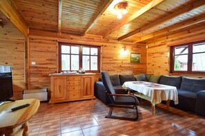 A wooden cabin interior with a sofa, a table, a cabinet, and a television. - Holiday home with 2 bedrooms (Dzwirzyno)