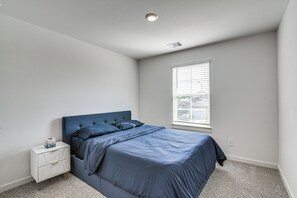 A bedroom with a bed, a nightstand, a window with blinds, and a ceiling light. - Modern Fresno Home w/ Yard: Near Parks & Shopping (Fresno)