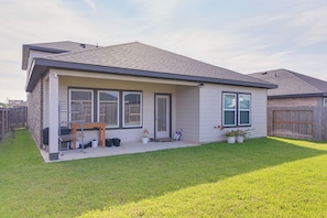 A residential house with a covered patio, a lawn, and a wooden fence. - Modern Fresno Home w/ Yard: Near Parks & Shopping (Fresno)