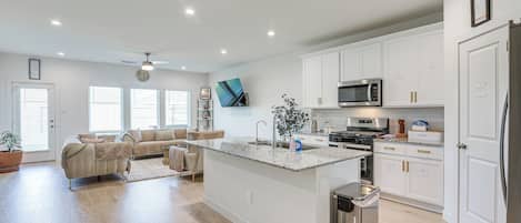 A modern kitchen with white cabinetry, a stainless steel refrigerator, a microwave, and a built-in oven.