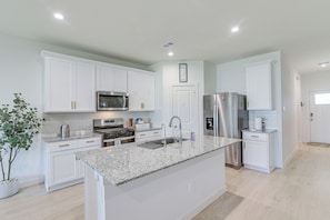A modern kitchen with white cabinetry, stainless steel appliances, and a granite countertop. - Modern Fresno Home w/ Yard: Near Parks & Shopping (Fresno)