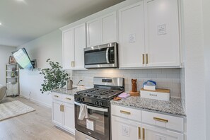 A modern kitchen with white cabinetry, stainless steel appliances, and a granite countertop. - Modern Fresno Home w/ Yard: Near Parks & Shopping (Fresno)
