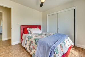 Ein Schlafzimmer mit einem Bett, einem roten Kopfteil, einem Kleiderschrank und Holzboden.