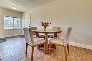 A dining area with a round table, four chairs, and a vase with red flowers. - Private Pool! Charming Clovis Escape (Clovis)