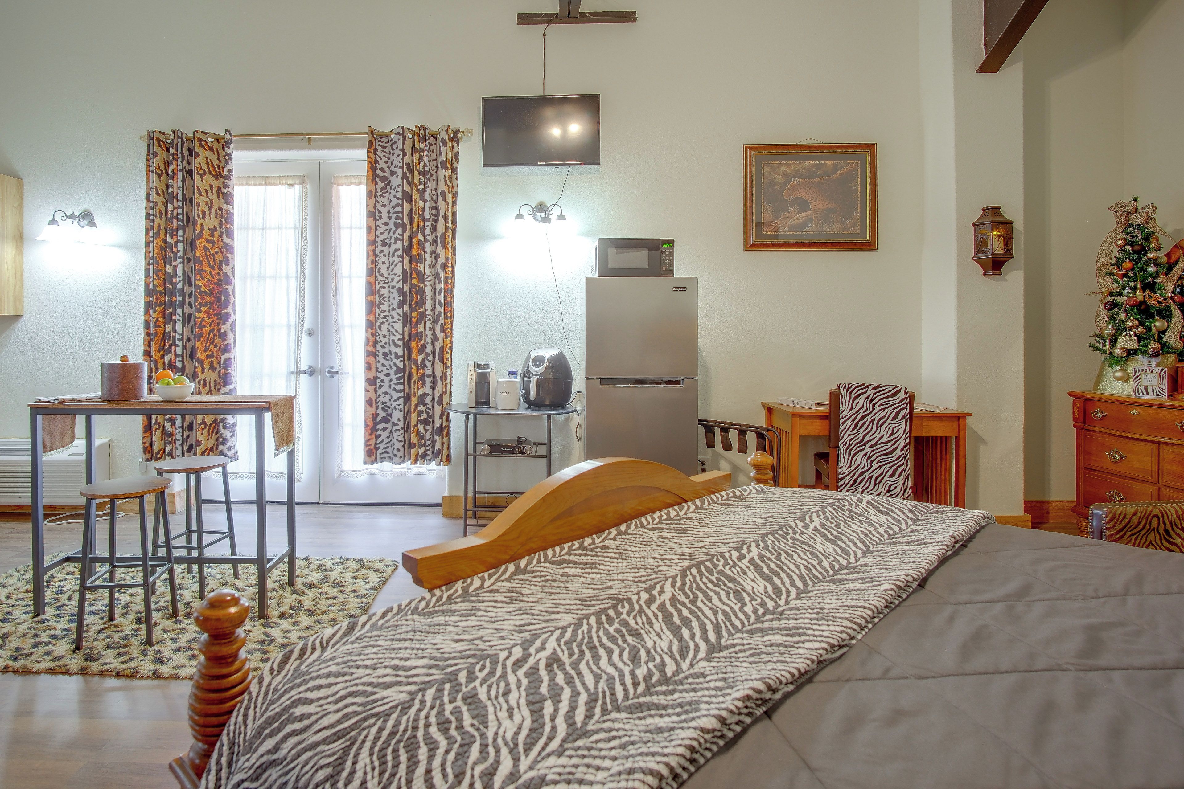 Un dormitorio con cama, escritorio, silla, refrigerador y televisión.