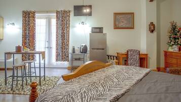 Ein Schlafzimmer mit Bett, Schreibtisch, Stuhl, Kühlschrank und Fernseher.
